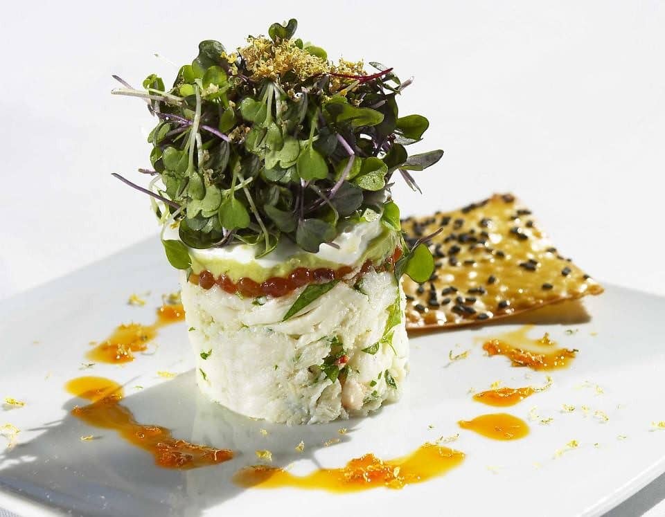 A plated starter crowned with a tumble of mixed microgreens